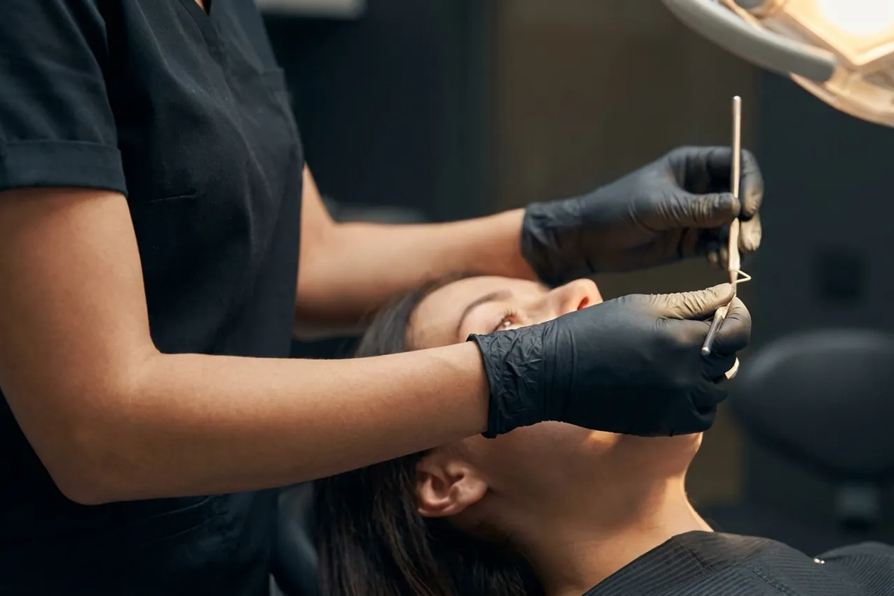Periodontista examinando a gengiva de um paciente em consulta